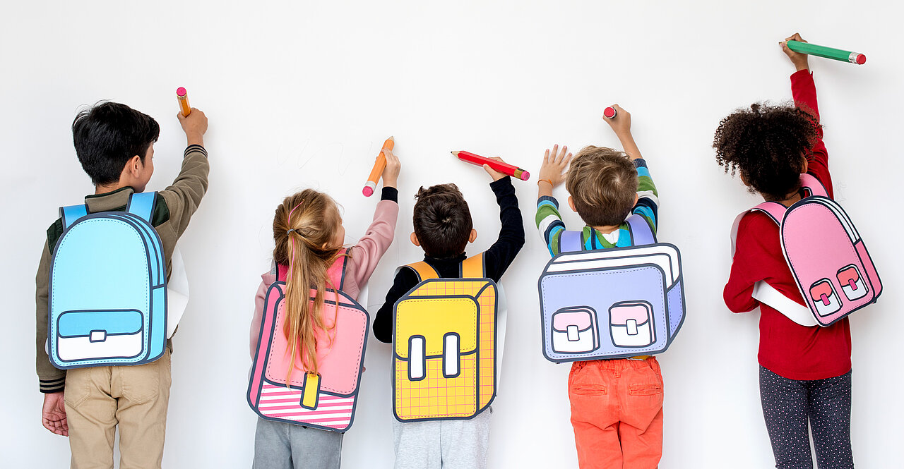 Enfants avec cartables qui dessinent sur un mur